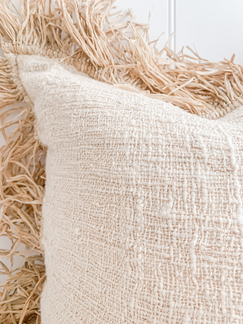 A close up of a Hanna | Linen Raffia Cushion with fringes made of natural raw cotton by Barre Living.