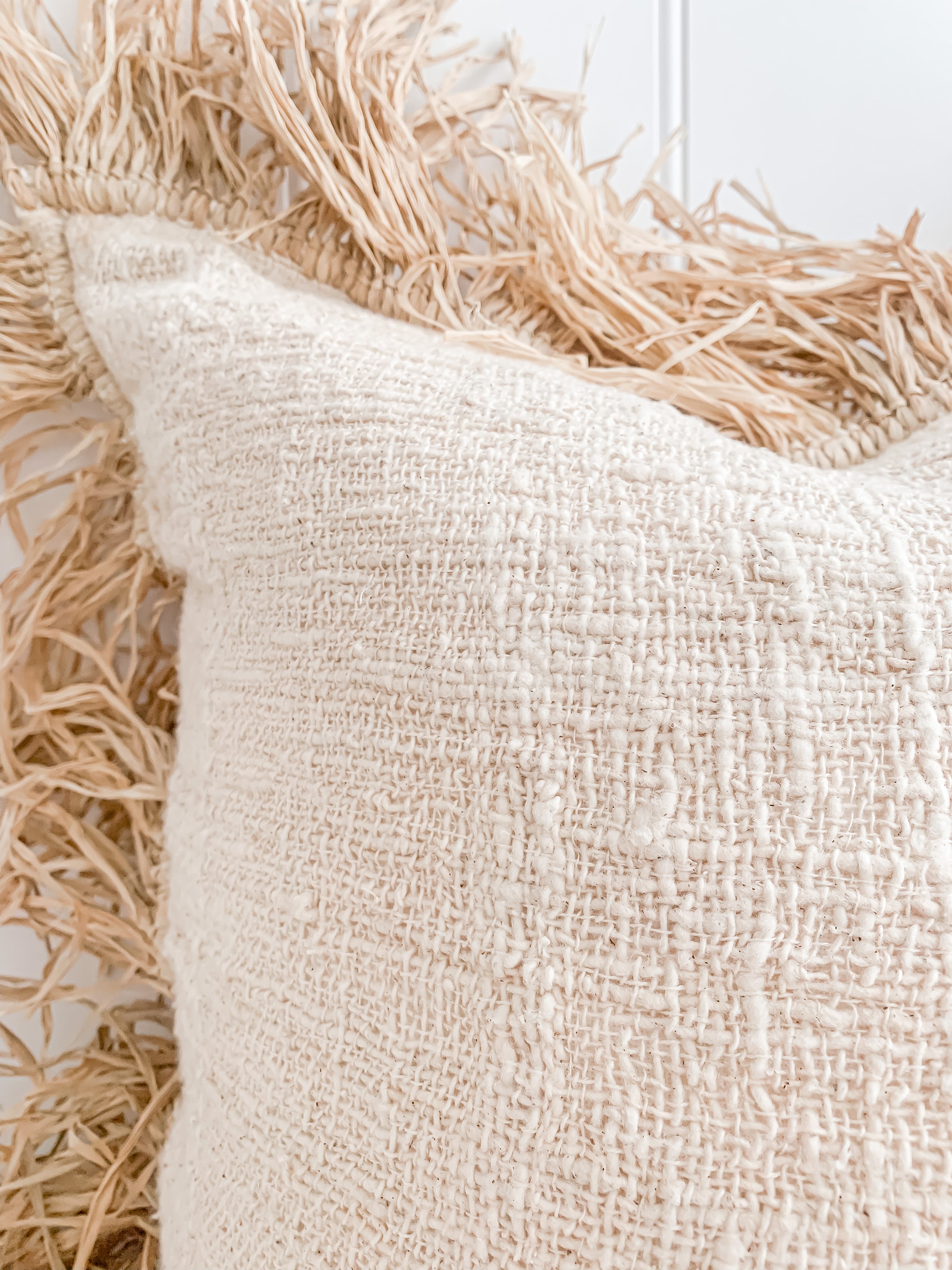 A close up of a Hanna | Linen Raffia Cushion with fringes made of natural raw cotton by Barre Living.
