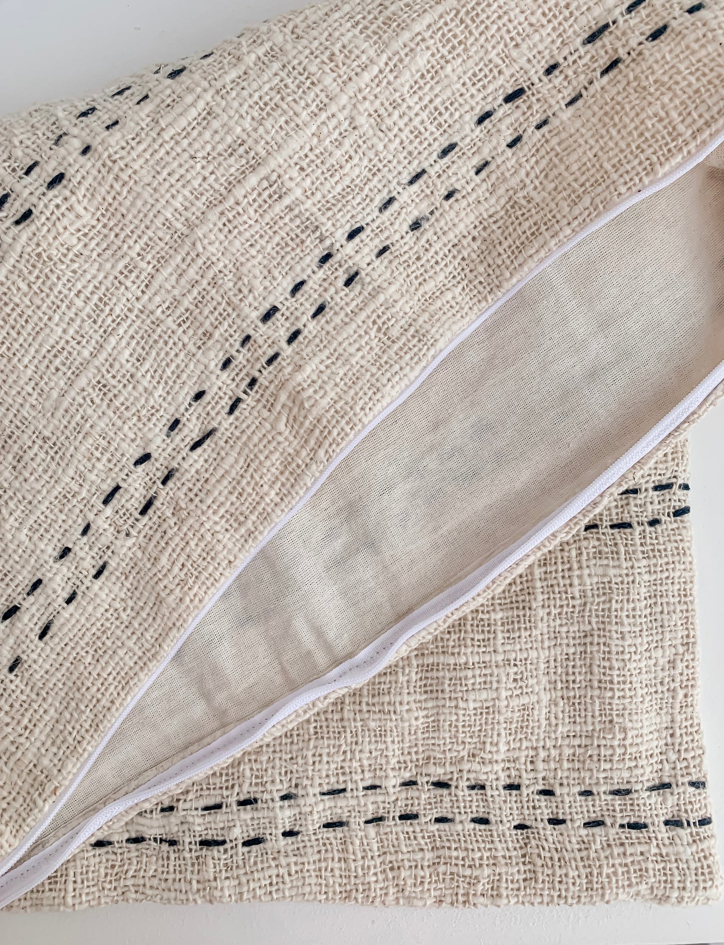 A Nyah | Stitch Cushion cover in a natural color with simple stitching by Barre Living.