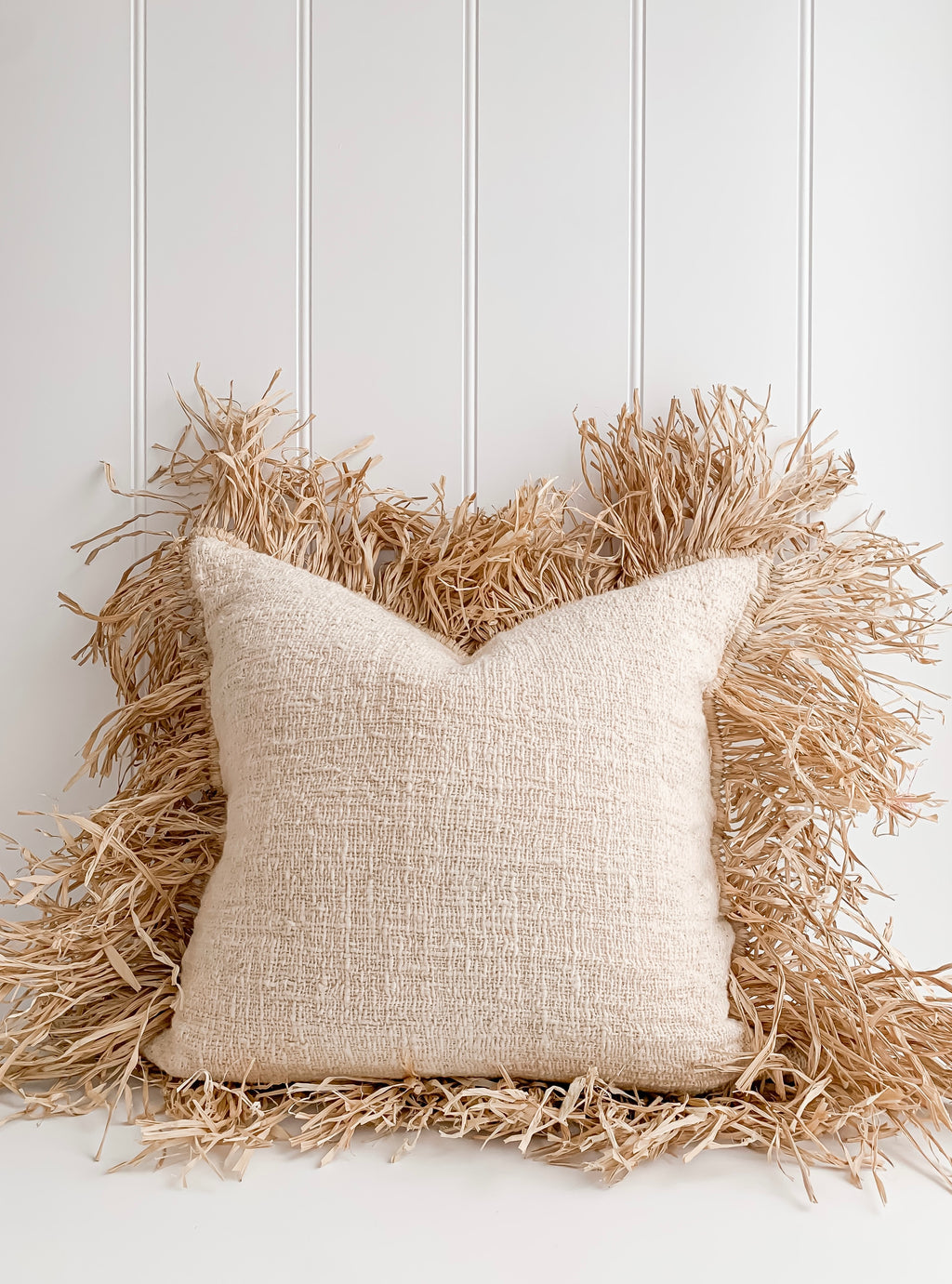 A Hanna | Linen Raffia Cushion made of natural raw cotton and adorned with raffia, by Barre Living.