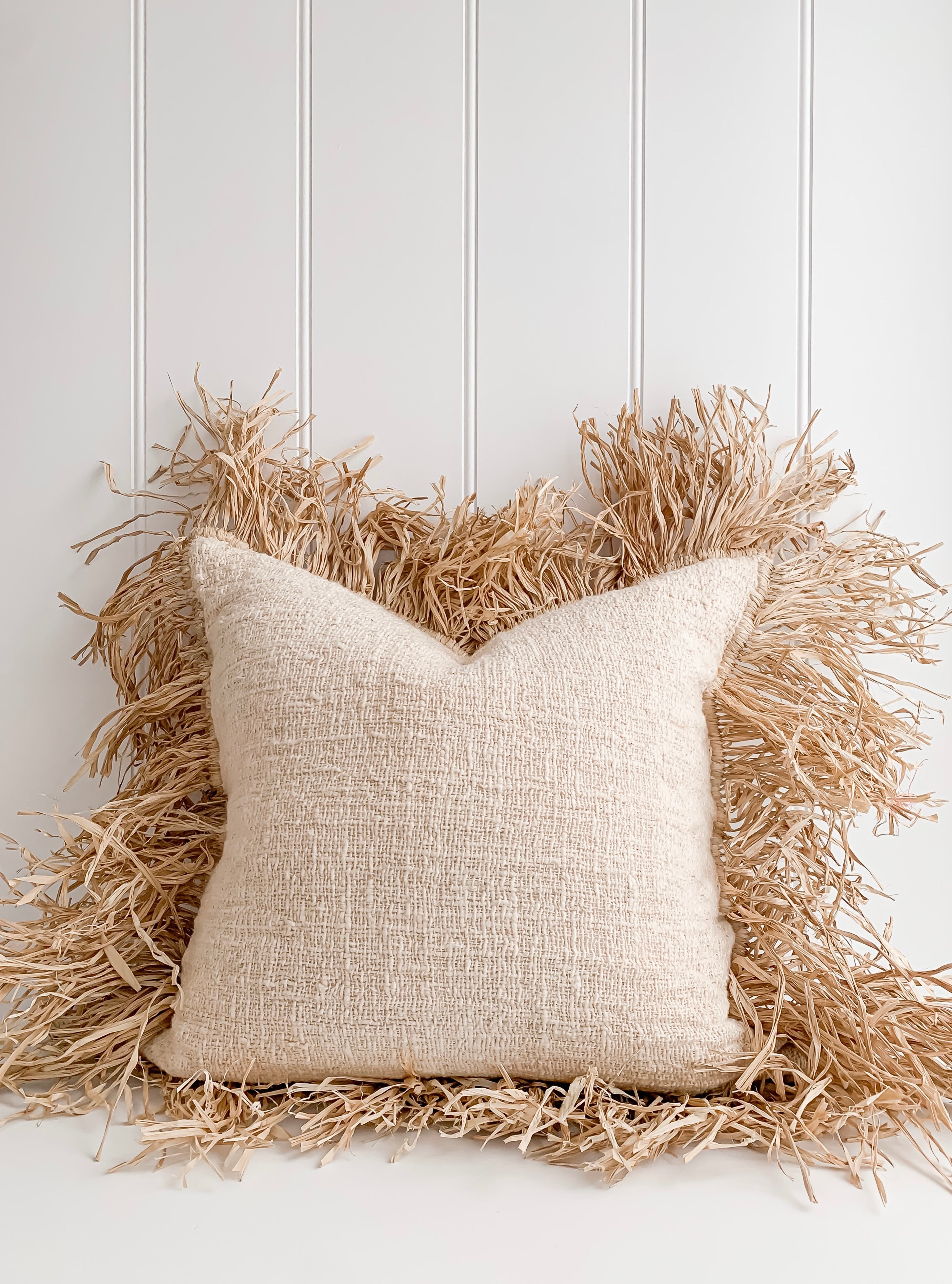 A Hanna | Linen Raffia Cushion made of natural raw cotton and adorned with raffia, by Barre Living.