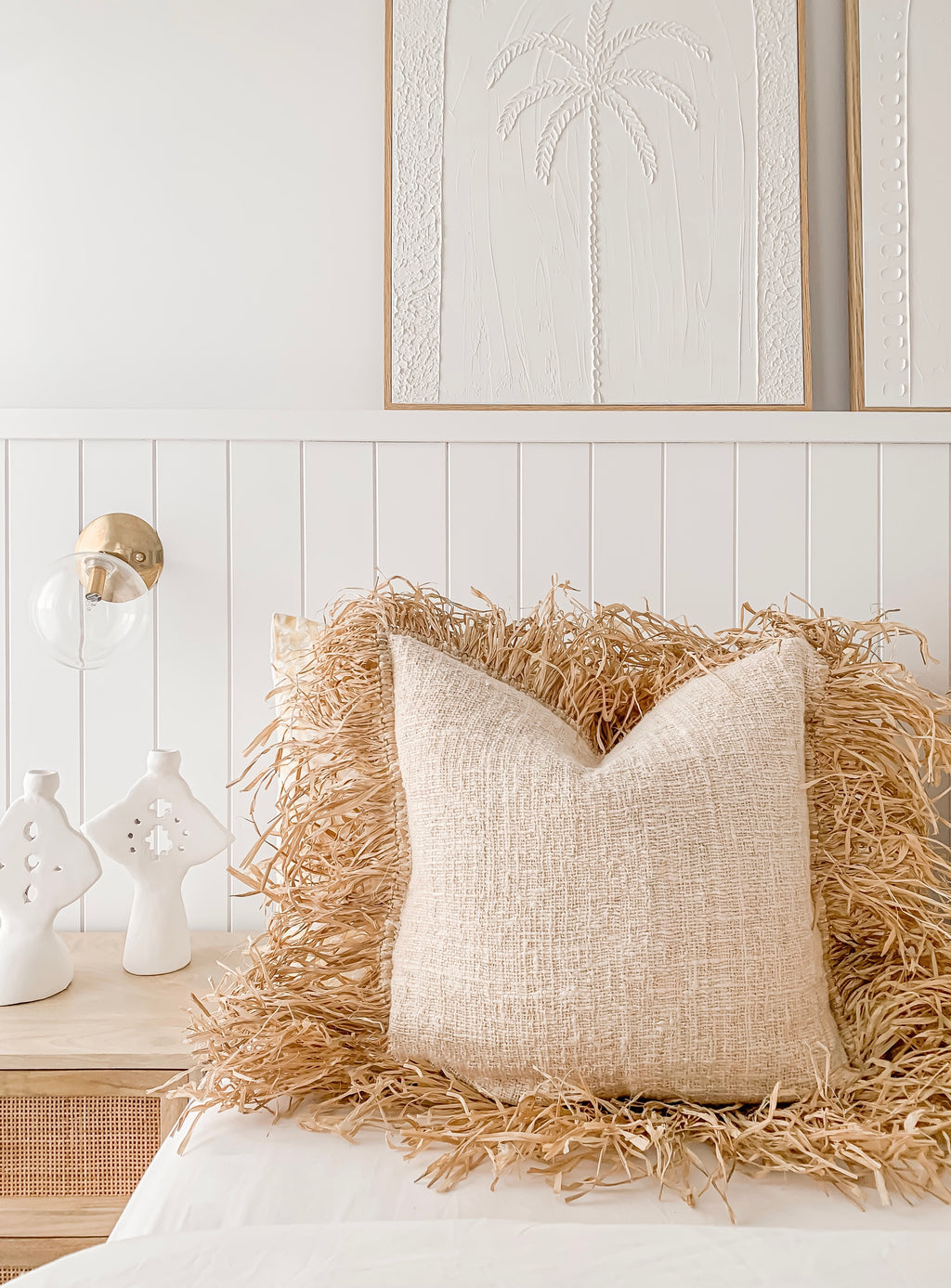A bedroom with a bed, pillows, and a bedside table featuring Barre Living's Hanna | Linen Raffia Cushion.