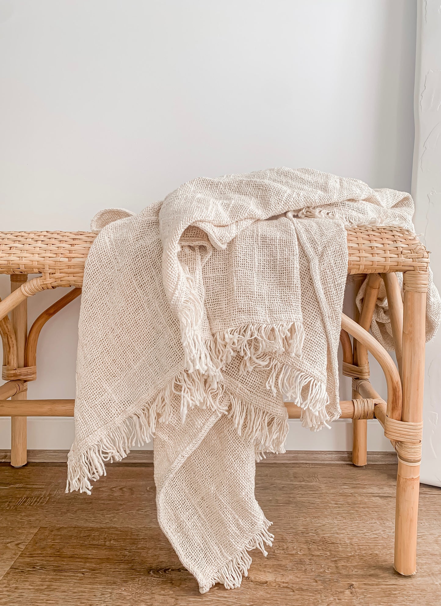 A Barre Living Arlo Throw on top of a rattan bench.