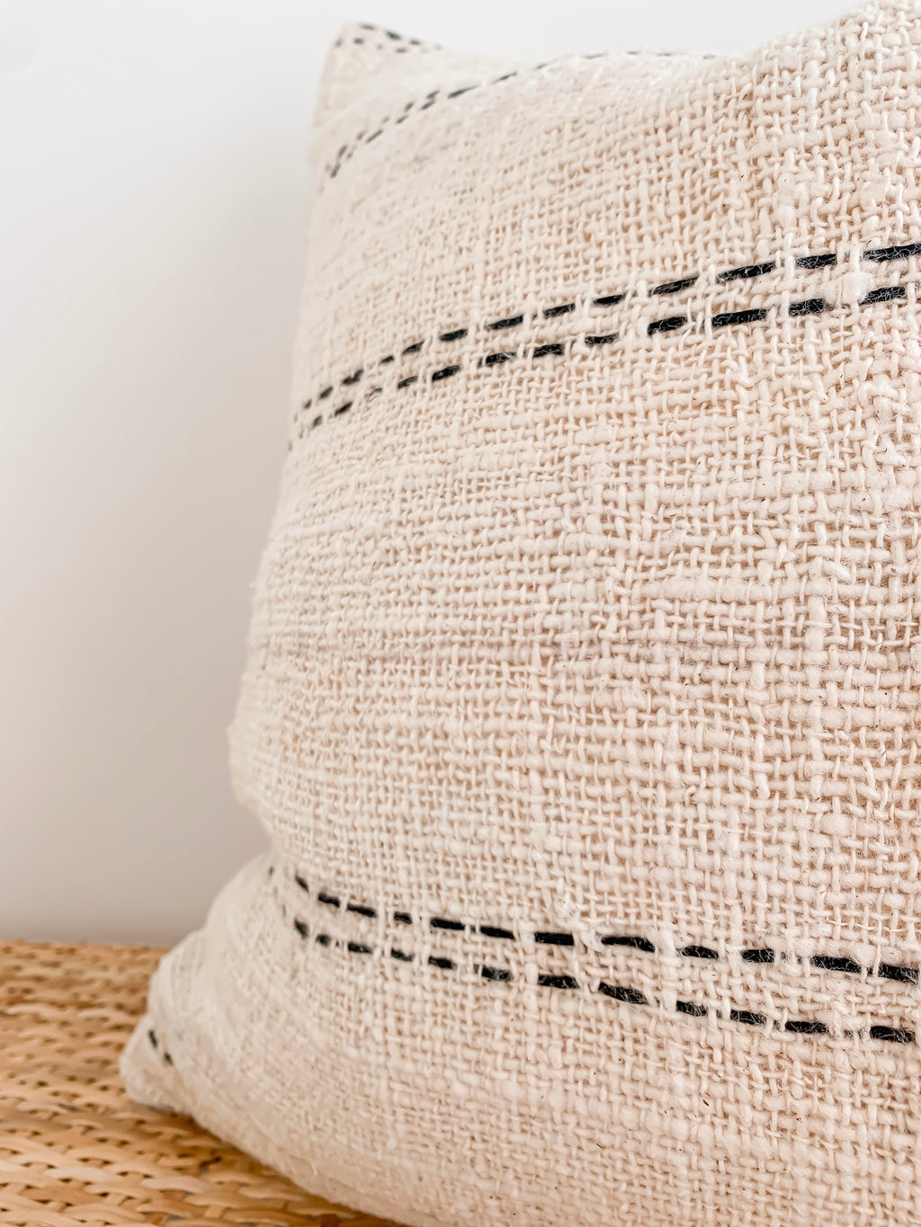 A Nyah | Stitch cushion cover in black and white stripes on a wooden table. (Brand: Barre Living)