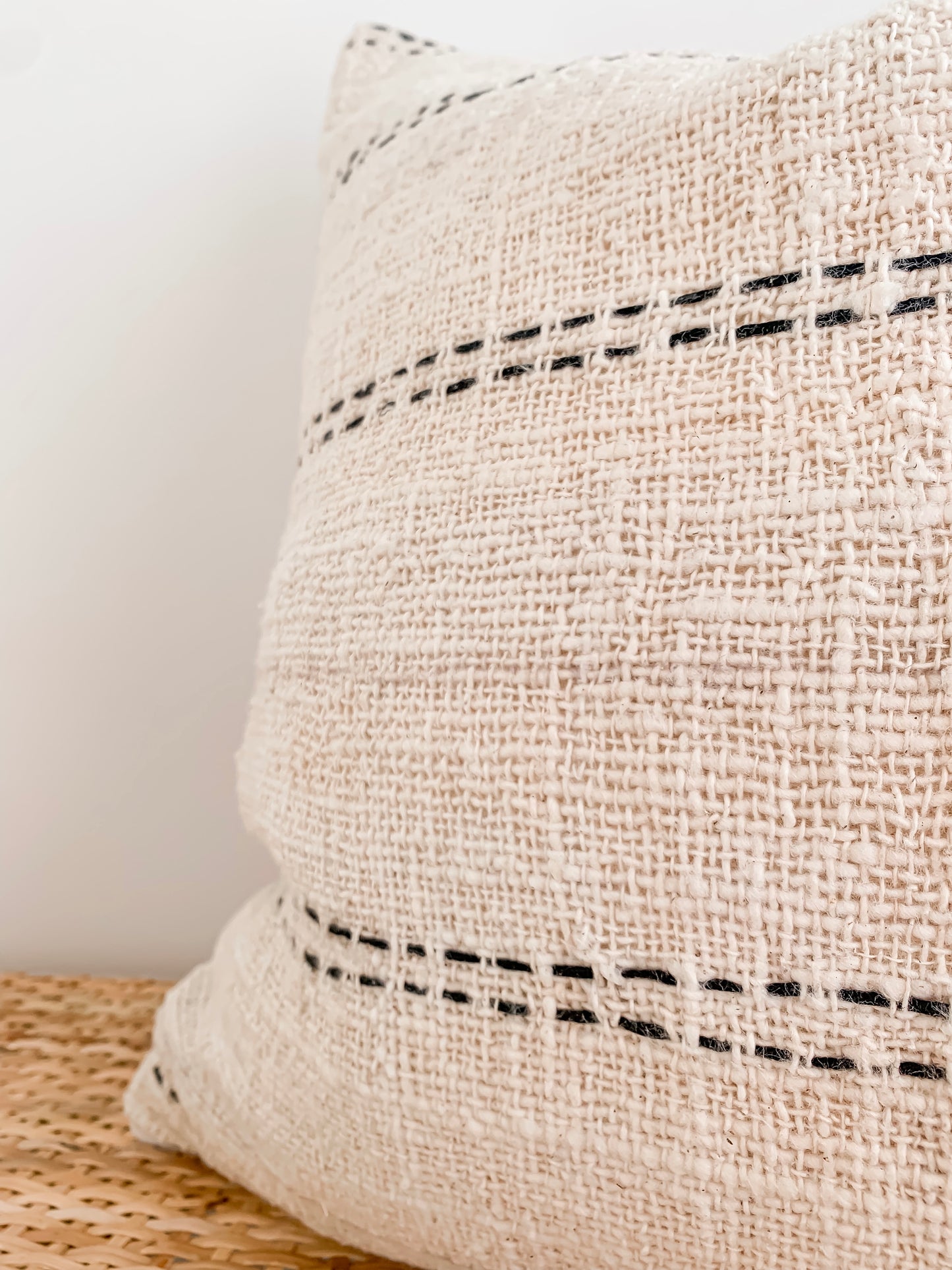 A Nyah | Stitch cushion cover in black and white stripes on a wooden table. (Brand: Barre Living)