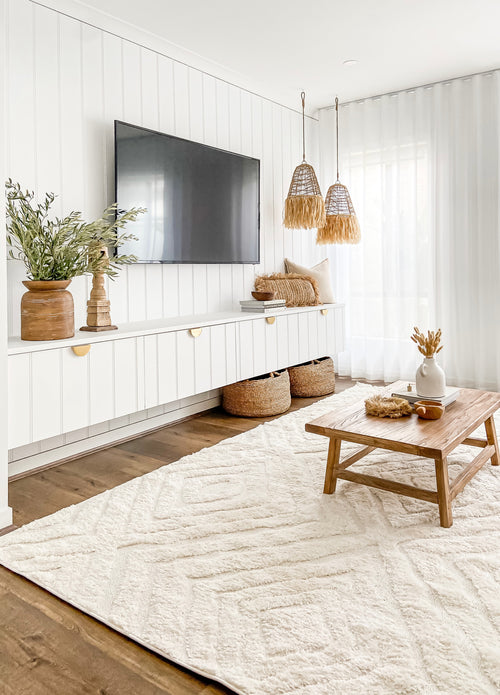 A living room with natural textures and modern design, featuring white walls and the Ellie Seagrass Pendant by Barre Living.