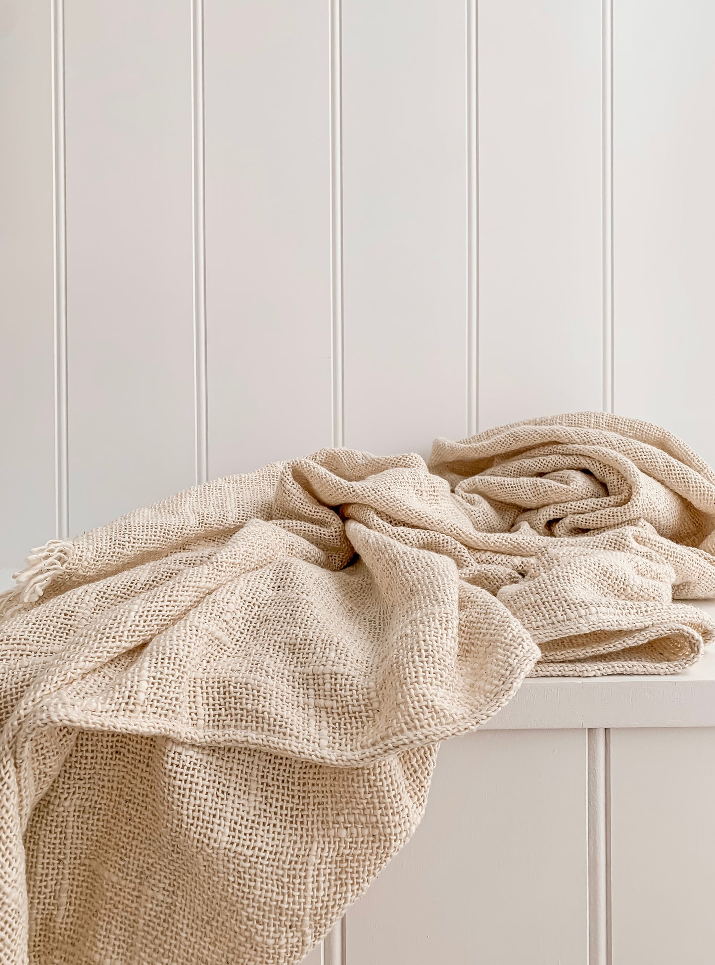 An Arlo throw on top of a white dresser by Barre Living.